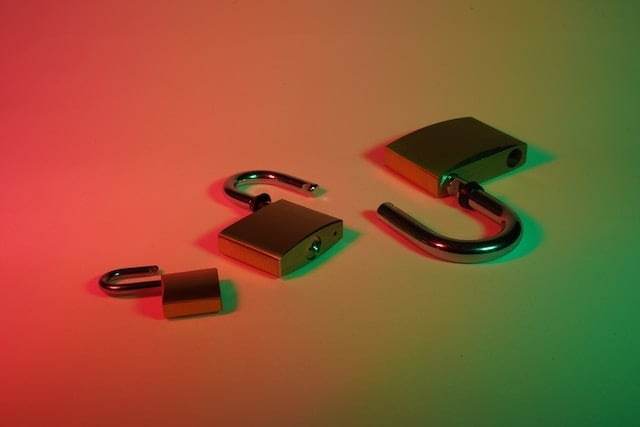 Three metal padlocks in various states of being unlocked on a surface with dramatic red to green gradient lighting