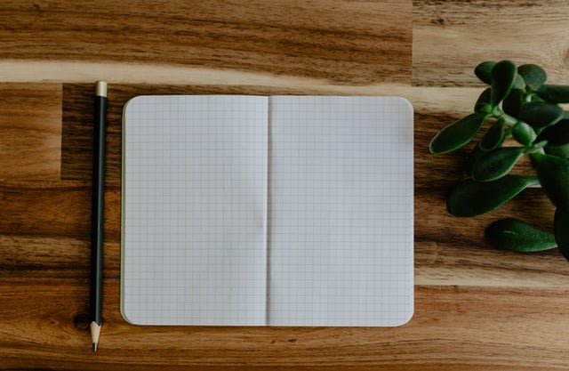 Blank open grid notepad laying on wooden table with pencil